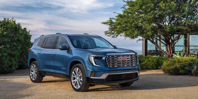 A GMC Acadia SUV parked in a scenic outdoor setting with lush greenery.