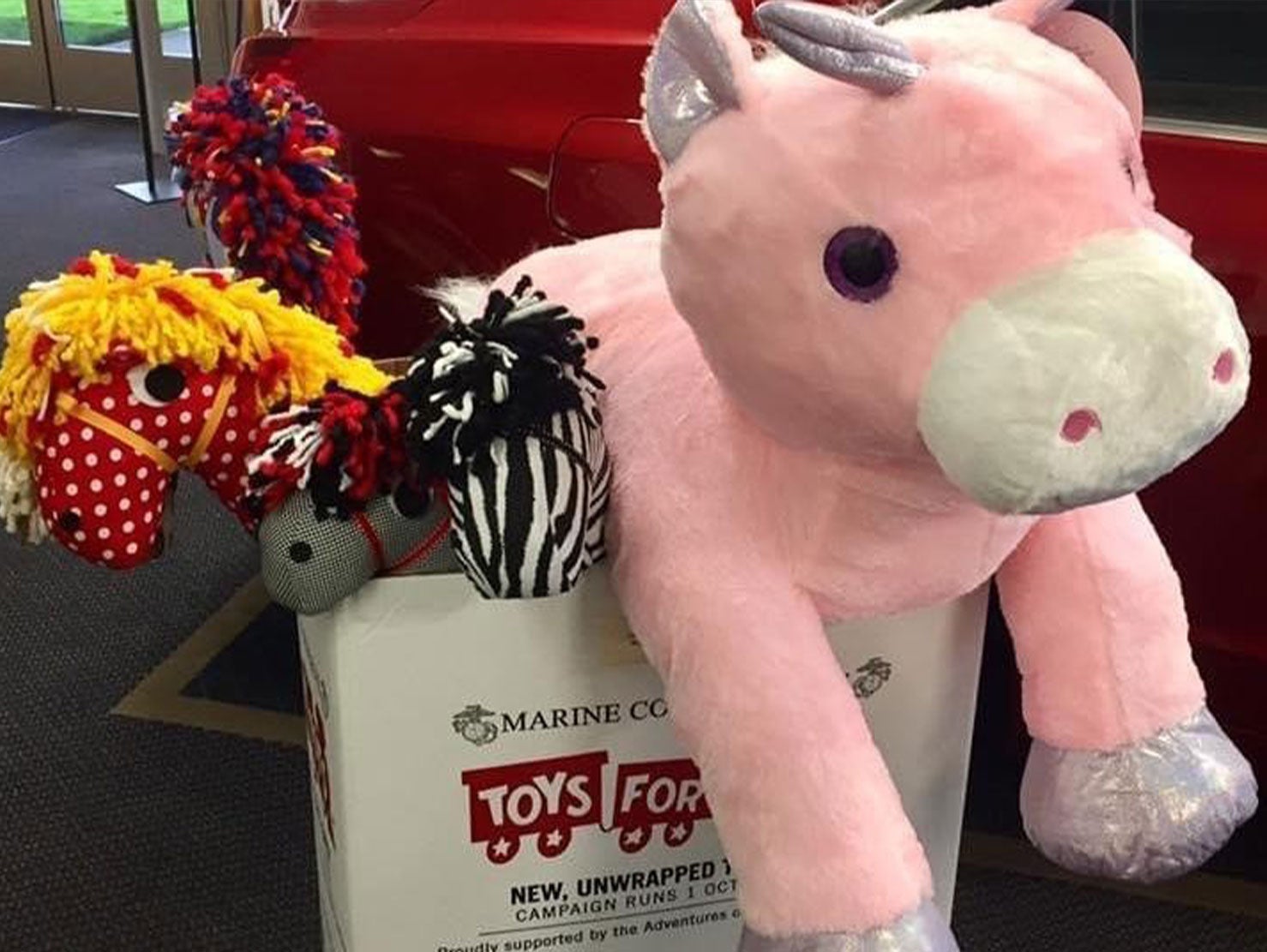 A large pink unicorn plush toy and several toys inside donation box. - Roe Motors in Grants Pass OR